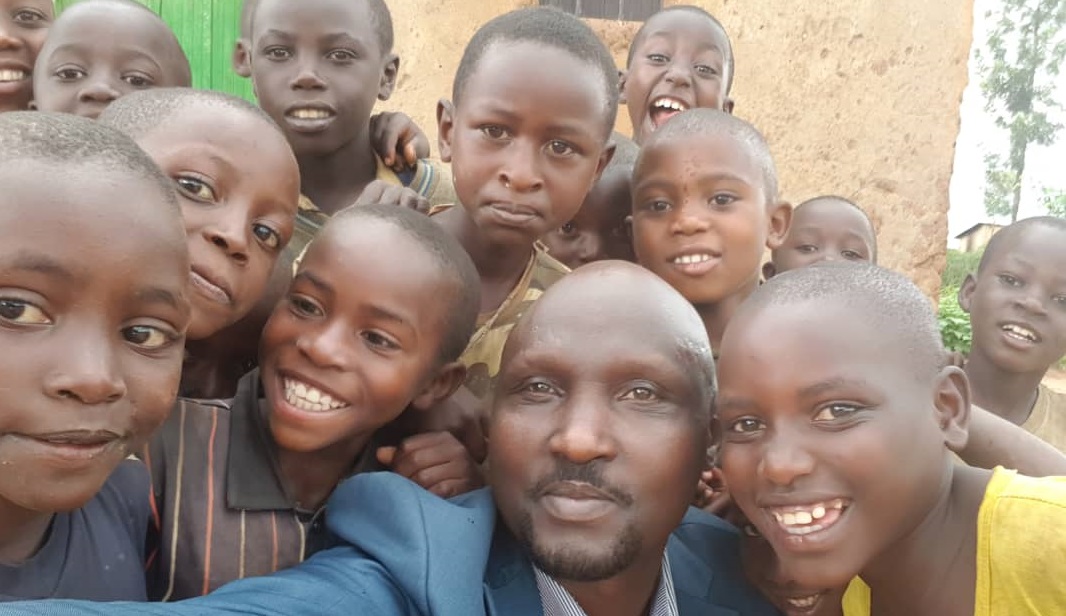 A Rwandan pastor surrounded by smiling children, all facing the camera